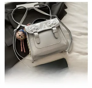 Close-up of silver bow backpack with metallic finish and cute plush toy keychain accessory