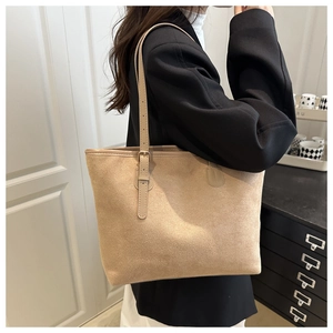 Détail d'un cabas en daim beige avec de fines lanières en cuir et une boucle en métal
