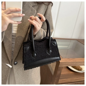 Detail of black faux shearling mini tote bag with smooth synthetic leather handles and trim
