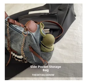 Detail view of denim tote bag side pocket holding a folding umbrella with brown leather trim