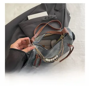 Detail of grey denim shoulder bag interior capacity showing phone and power bank storage