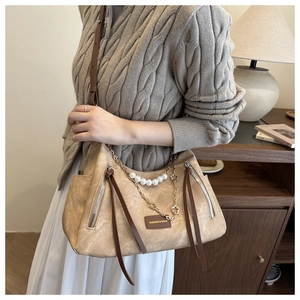 Detail of vintage beige shoulder bag with pearl chain decoration and fringe zippers