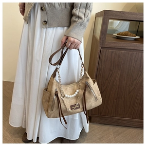 Detail of khaki suede tote bag with pearl chain accents and metal zipper ribbons