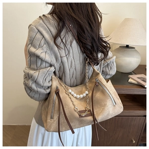 Close-up of khaki shoulder bag with pearl chain, metallic tassels, and fashion patch