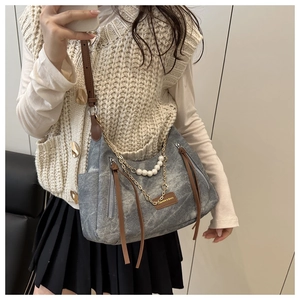 Close-up of grey denim shoulder bag with pearl chain and leather tassel detail