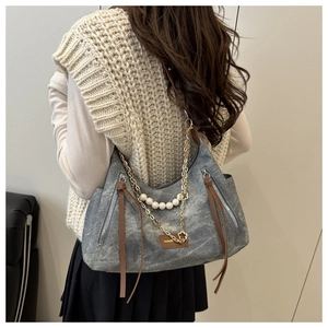 Detail view of grey canvas hobo bag with pearl chain and leather fashion label