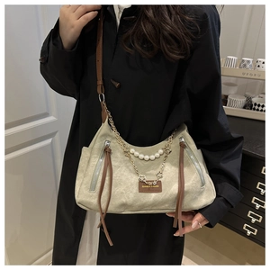 Detail of canvas tote bag with pearl chain decoration and brown leather brand label