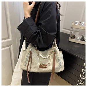 Detail of vintage canvas tote with gold chains, pearls, and leather strap trim