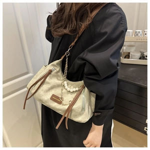 Close-up of light green shoulder bag featuring elegant pearl chain and leather zipper