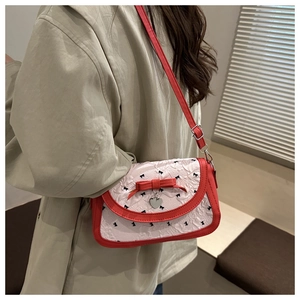 Détail du sac à bandoulière nœud rouge et blanc avec pendentif cœur et tissu texturé