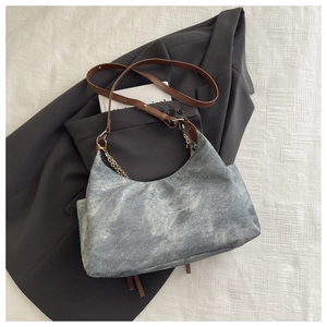 Detail of grey washed canvas bag with brown leather strap and gold chain link