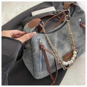 Detail of vintage grey denim handbag featuring premium leather straps and pearl chain