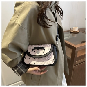 Vue détaillée d'un sac bandoulière rose à motif nœuds avec ruban noir et breloque cœur