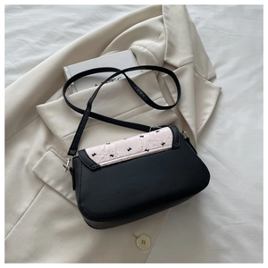 Détail du sac bandoulière en cuir noir avec rabat plissé rose et broderie de nœud noir