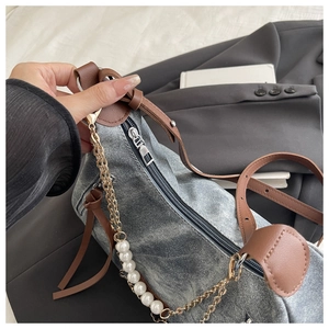 Detail of vintage gray denim handbag featuring pearl chain and silver metal accents