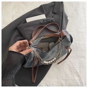 Detail of grey canvas handbag with pearl chain, leather strap and spacious interior
