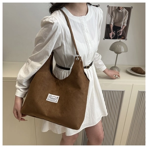 Brown frosted leather hobo bag with slim strap and white label worn by a model