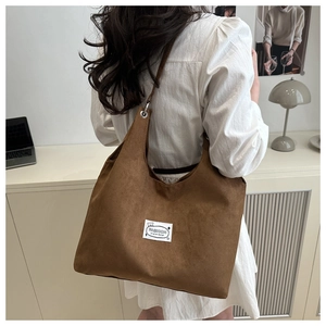 Detail of a brown faux suede tote bag featuring a Fashion label and a soft matte finish