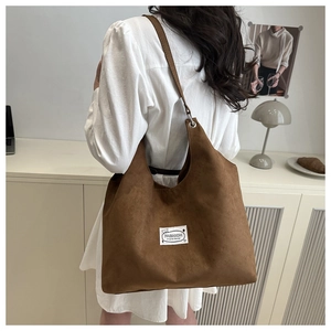 Borsa tote in camoscio opaco marrone con etichetta in un ambiente minimalista