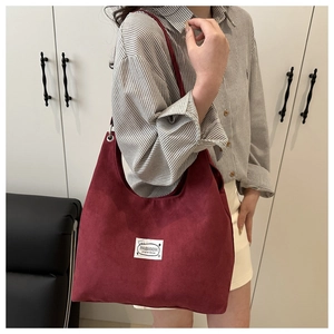 Dettaglio della borsa tote in pelle scamosciata bordeaux con ricamo e tracolla larga