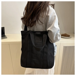 Détail du grand sac cabas en toile noire avec étiquette Fashion Instinct et design spacieux