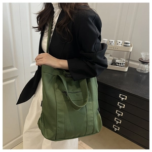 Détail du sac cabas en toile vert foncé montrant la poche zippée et l'étiquette Fashion