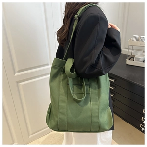 Sac fourre-tout en toile vert olive profond porté par un mannequin en vue latérale