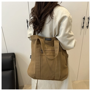 Détail du sac cabas en toile marron montrant la vue latérale avec bandoulière et étiquette