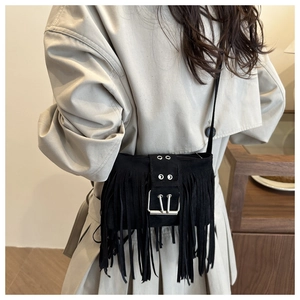 Detail of black suede crossbody bag with long fringes and metal buckle on trench coat