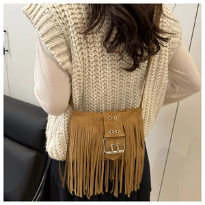 Detail of brown suede bucket bag featuring long fringe and vintage metal buckle decoration