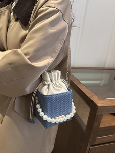 Blue woven bucket bag with pearl handle and white drawstring liner on model