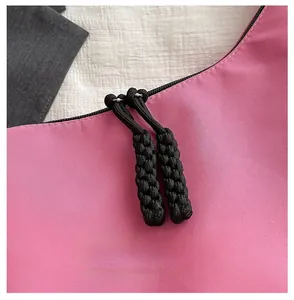 Detailed close-up of smooth black zippers with woven pullers on a pink nylon bag
