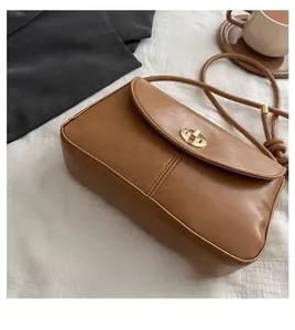 Detail of vintage brown shoulder bag with golden twist lock and knotted strap on white fabric