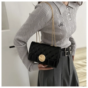 Détail du sac à bandoulière noir matelassé avec fermoir doré et bandoulière chaîne