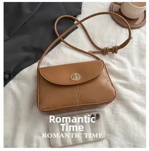 Brown leather crossbody bag with metal lock shown next to phone for size comparison