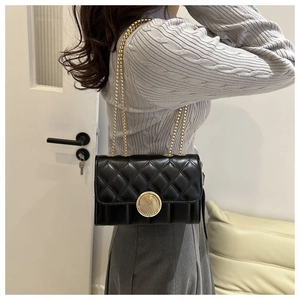 Détail d'un sac bandoulière en cuir matelassé noir avec fermoir doré en forme d'empreinte