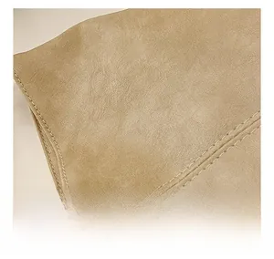 Macro shot of durable leather texture and precise double stitching on a khaki tote bag