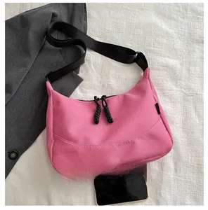 Pink nylon hobo bag shown with a smartphone for scale comparison on striped fabric