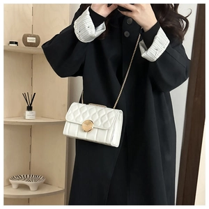 Détail du sac à bandoulière blanc matelassé avec chaîne dorée et boucle métallique