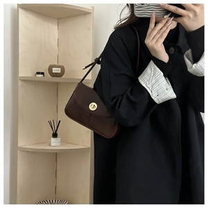 Detail shot of vintage dark brown crossbody bag with gold metal clasp on a model