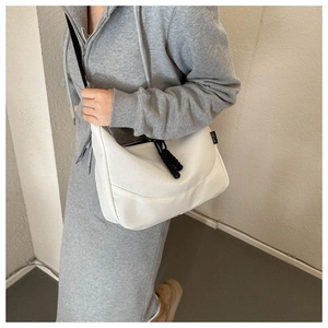 Detail view of the white nylon shoulder bag featuring a black SPORT label and zipper tassels