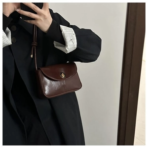 Detail of dark brown vintage leather crossbody bag featuring a golden twist lock closure
