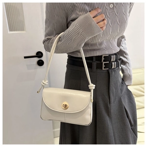 Detail of cream white leather handbag with knotted shoulder strap and gold twist lock