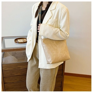 Detail of light brown leather tote bag featuring a vintage patterned fabric shoulder strap