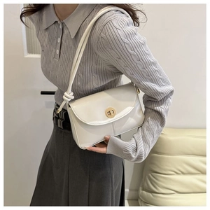 Detailed view of a white minimalist shoulder bag with a gold metal twist lock and knotted strap