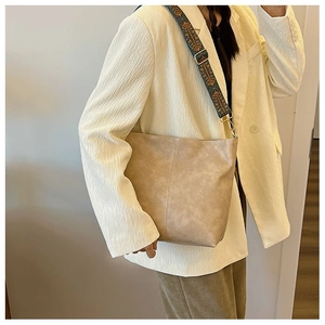 Detail of vintage jacquard strap and side stitching on beige large capacity bucket bag