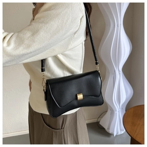 Model wearing a black minimalist leather crossbody bag with a gold square metal buckle