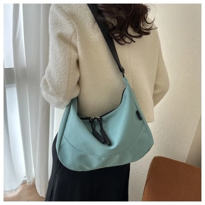 Detail of mint green nylon crescent bag featuring black dual zippers and braided rope accents