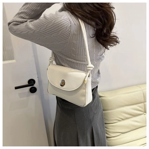 Close-up of ivory shoulder bag featuring a metallic twist lock and knotted strap detail