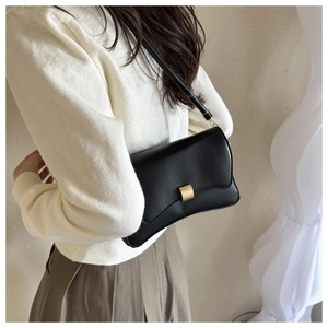 Side view of a black leather rectangular baguette bag with a gold square clasp on a shoulder